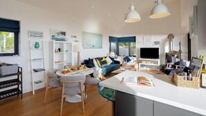 A modern living room with a sofa, dining table, and kitchen area. - Seagrass - Dog Friendly-Hot Tub-Sea Views-Sleeps 4 (Ventnor)