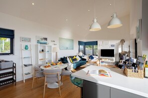 A modern living room with a sofa, dining table, and kitchen area.