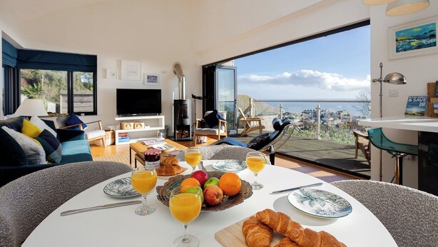 A modern living room with a dining area, a fireplace, and a scenic view. - Seagrass - Dog Friendly-Hot Tub-Sea Views-Sleeps 4 (Ventnor)