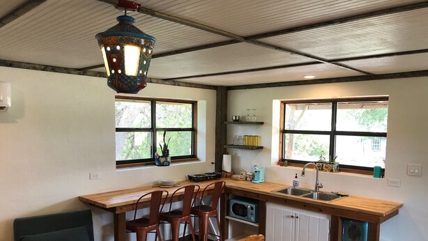 Une cuisine compacte dotée d’un plan de travail en bois, d’un luminaire suspendu et d’une fenêtre donnant sur la verdure.