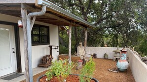 Un espace extérieur rustique agrémenté d’une structure en bois, d’un bac à fleurs bleu contenant des plantes et d’une lanterne en pierre.