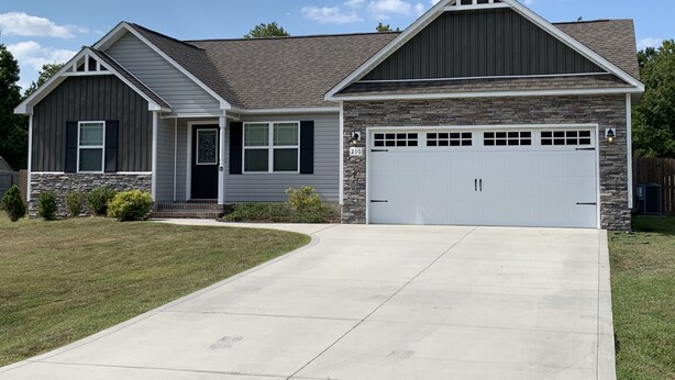 A two-story house with a stone facade, a garage, and a driveway. - Sea You Soon- 1 mile to Camp Lejeune! Monthly rental- fully furnished!  (Hubert)