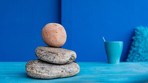Un conjunto de tres piedras, con una taza azul al fondo.