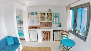 Cocina compacta con refrigerador, estufa y armarios. Se ve una ventana con vista al exterior.