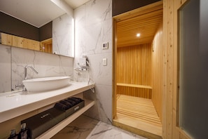 A modern bathroom with a large white sink, wooden vanity, marble walls, and a wooden sauna area. - Hotel Maria (Pyeongtaek)