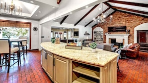 Una cocina amplia con una isla grande, un comedor con mesa y sillas, y una sala de estar con chimenea y asientos.