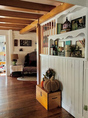 A cozy living room with a wooden floor, a sofa, a table with a lamp, and a decorative shelf with various items. - Located in Ephraim, in the heart of Door County (Sister Bay)