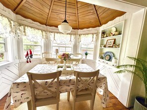 A dining area with a wooden ceiling, white walls, and a table set with a floral tablecloth. - Located in Ephraim, in the heart of Door County (Sister Bay)