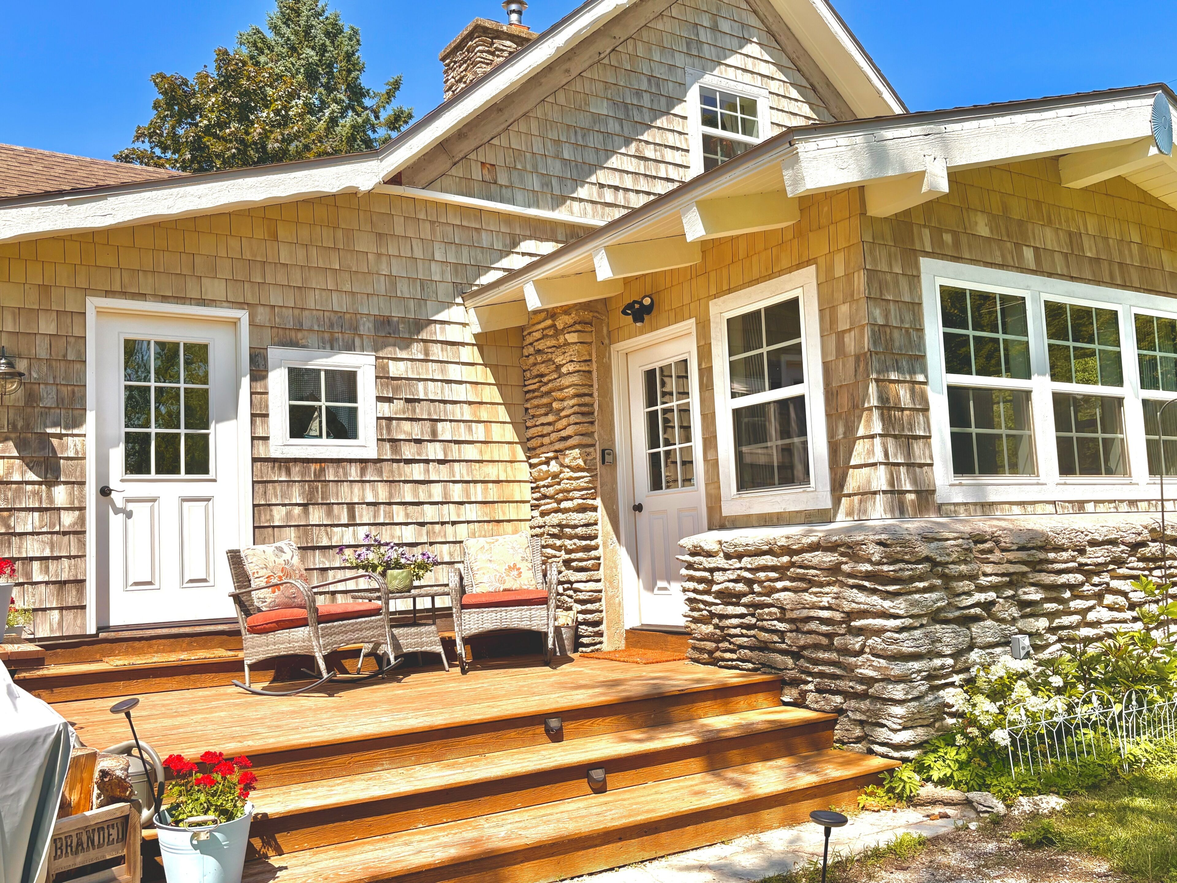 A wooden house with a stone staircase leading to a porch, a door, and a window.
