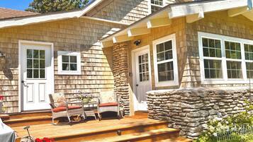 A wooden house with a stone staircase leading to a porch, a door, and a window.