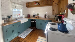 A kitchen with white subway tiles, wooden cabinets, a white stove, and a blue kettle. - Located in Ephraim, in the heart of Door County (Sister Bay)