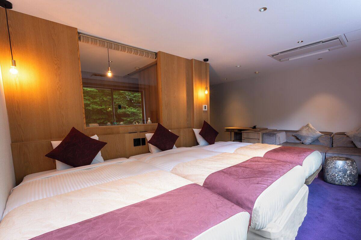 Habitación de hotel con una cama grande, cabecera de madera, un espejo y vistas a zonas verdes.