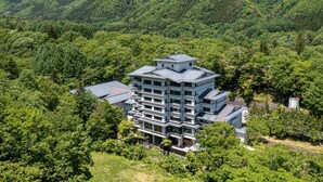 Un hôtel à plusieurs étages, doté d’une architecture moderne, et entouré de collines verdoyantes et luxuriantes.