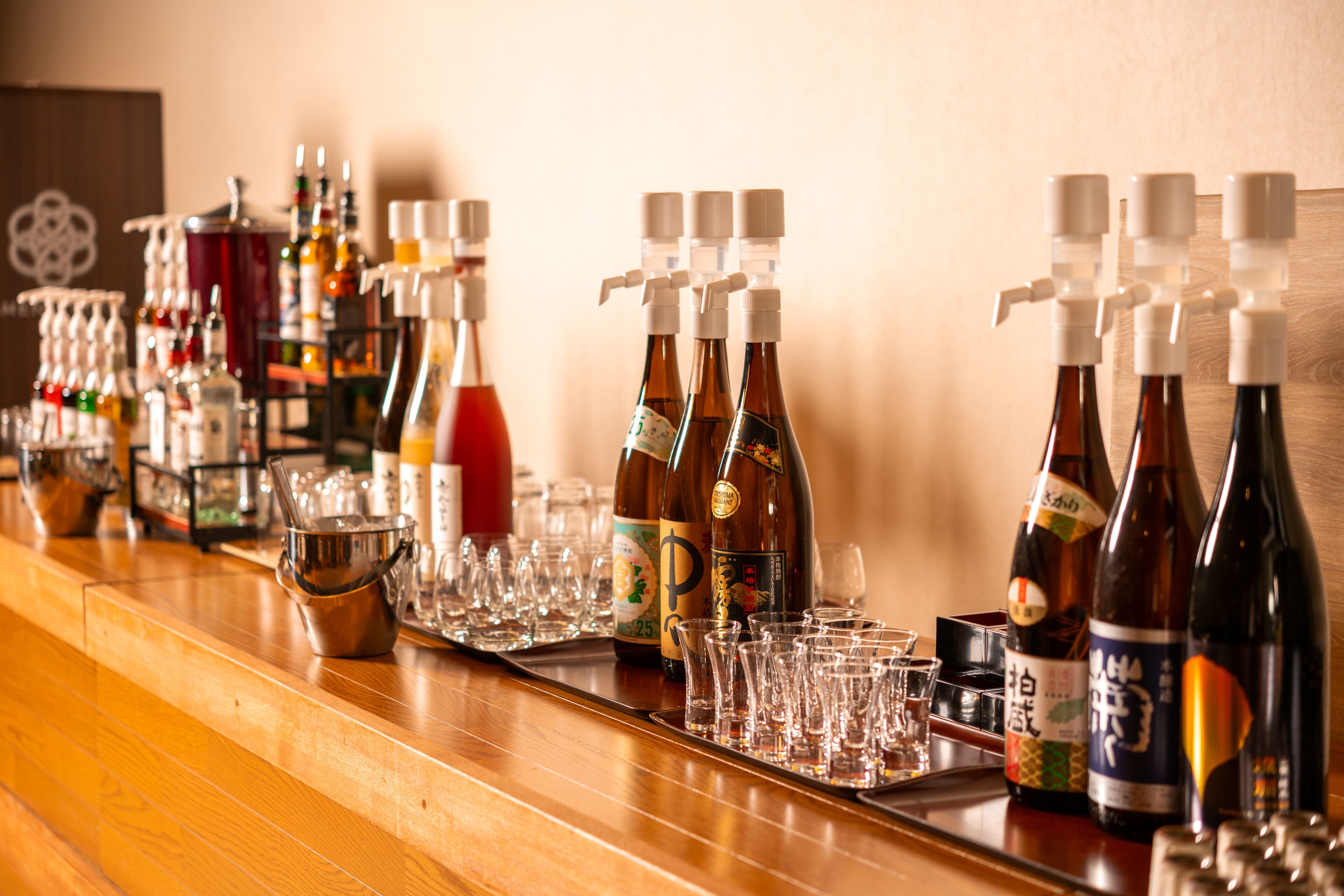 Un bar avec différentes bouteilles et différents verres disposés sur un comptoir en bois.
