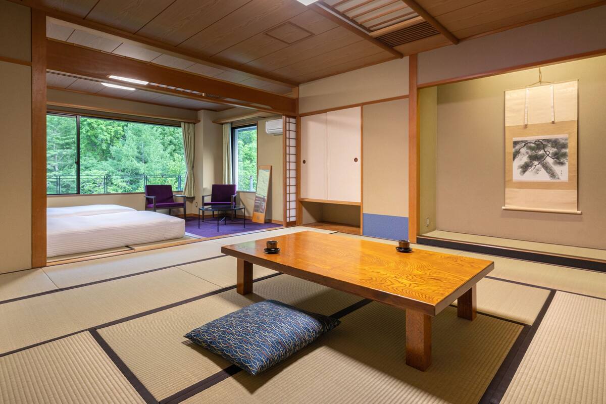 Una habitación tradicional japonesa con suelo de tatami, una mesa de madera baja y una cama futón.