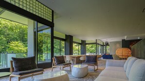 Un vaste espace de vie doté de grandes fenêtres, d’un canapé, de fauteuils et d’une table ronde.