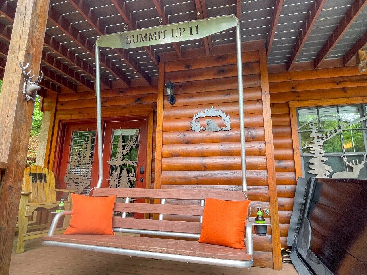 A wooden cabin with a bench, a sign reading 'SUMMIT UP 11', and a deer head decoration.
