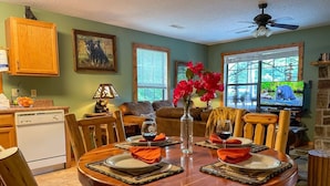 A dining area with a round wooden table set for four, surrounded by wooden chairs. - Romantic Private Cabin | Hot Tub | Mtn Views, Pets (Sevierville)