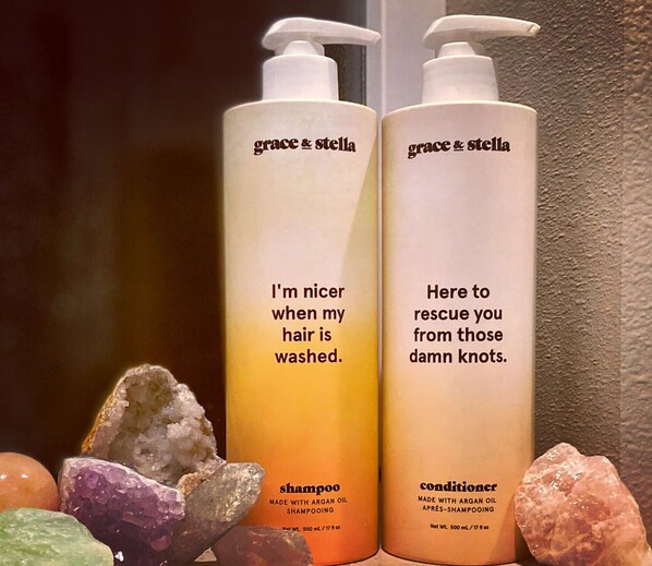 Dos botellas de productos para el cabello Grace & Stella, una de champú y otra de acondicionador, con un fondo de cristales de colores.