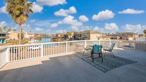 A balcony with a view of a marina, a pool, and residential buildings.