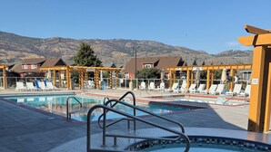 Un área de piscina con solárium empinado, sillas de descanso y una estructura de pérgola de madera.