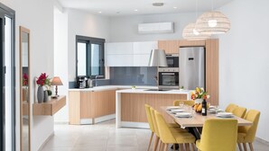 A modern kitchen with a central island, built-in appliances, and a dining area with yellow chairs.