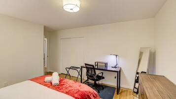 A bedroom with a bed, a desk, a chair, and a mirror.