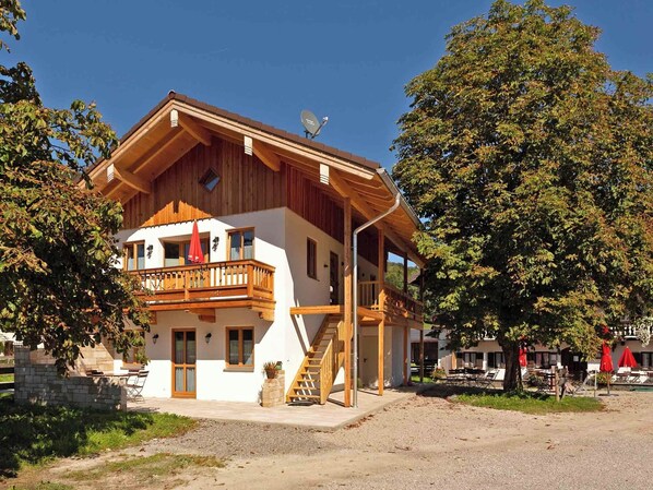 Un chalet en bois à deux étages, doté d’un balcon et d’une antenne parabolique.