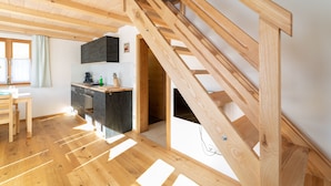 Eine moderne Küche mit Holzbalken, einem Essbereich und einer Treppe.