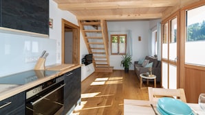 Eine moderne Küche mit Holzbalkendecke, einer Treppe, einer Couch und einem Essbereich mit Tisch und Stühlen.