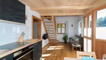 Eine moderne Küche mit Holzbalkendecke, einer Treppe, einer Couch und einem Essbereich mit Tisch und Stühlen.