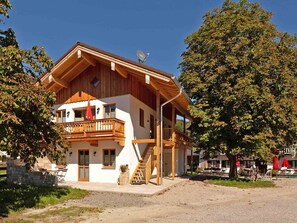 A two-story wooden building with a balcony, a satellite dish, and a staircase leading to the upper floor.