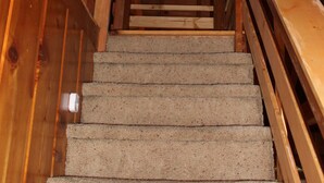 A wooden staircase with a carpeted landing. - Rustic Chapparal Cabin at Bass Lake Heights (Oakhurst)