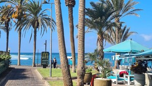 A pathway lined with palm trees leading to a beach area with a McDonald's sign, outdoor seating, and a blue umbrella. - 145 m2 apartment with complex view, bar-restaurant, swimming pools, sea 300 m from the sea (Adeje)