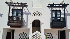 A white building with two balconies, a central archway, and a stone-paved entrance. - 145 m2 apartment with complex view, bar-restaurant, swimming pools, sea 300 m from the sea (Adeje)