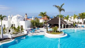 A resort pool area with clear blue water, lounge chairs, palm trees, and white buildings with domed roofs. - 145 m2 apartment with complex view, bar-restaurant, swimming pools, sea 300 m from the sea (Adeje)