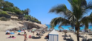 A beach with thatched umbrellas, lounge chairs, and a small building, likely a beach hut. - 145 m2 apartment with a view of the complex, bar-restaurant, swimming pools, and the sea—300 m from the beach (Adeje)