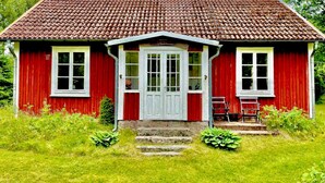 A red wooden house with a tiled roof, a front door, and a small porch. - Rosenlund - Holiday cottage Rosenlund (Älmhult)