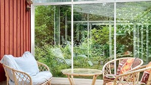 A covered patio with wicker furniture and a glass enclosure. - Rosenlund - Holiday cottage Rosenlund (Älmhult)
