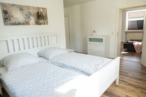 A bedroom with a bed, a nightstand, a dresser, and a painting on the wall. - Beautiful vacation apartment in Oberkotzau am Fichtelgebirge (Oberkotzau)