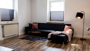 A modern living room with a black sofa, a small round coffee table, and a floor lamp.