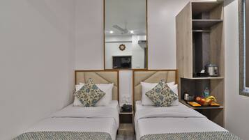 A hotel room with two beds, a mirror, a wardrobe, and a small table with a fruit tray.