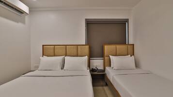 Ein Hotelzimmer mit zwei Einzelbetten, einem kleinen Nachttisch, einem Beistelltisch und einem Fenster mit Blick.