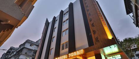 Un hotel con fachada moderna, varios pisos y un cartel llamativo que dice "Hotel 7-Orbit".