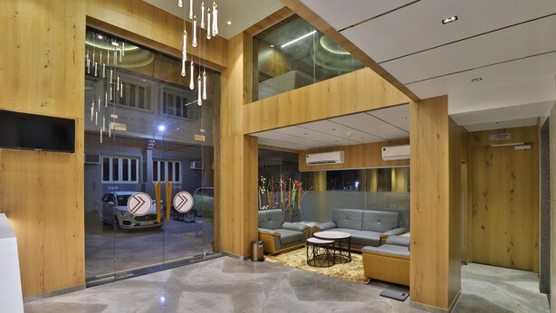 Um lobby moderno com interior em madeira, área de estar e uma parede de vidro com vista para carros.