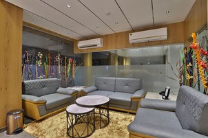 A modern living room with grey sofas, round tables, and decorative plants.