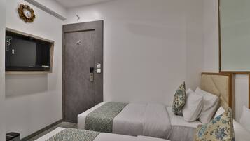 A hotel room with two beds, a wardrobe, a TV mounted on the wall, and a small trash bin.