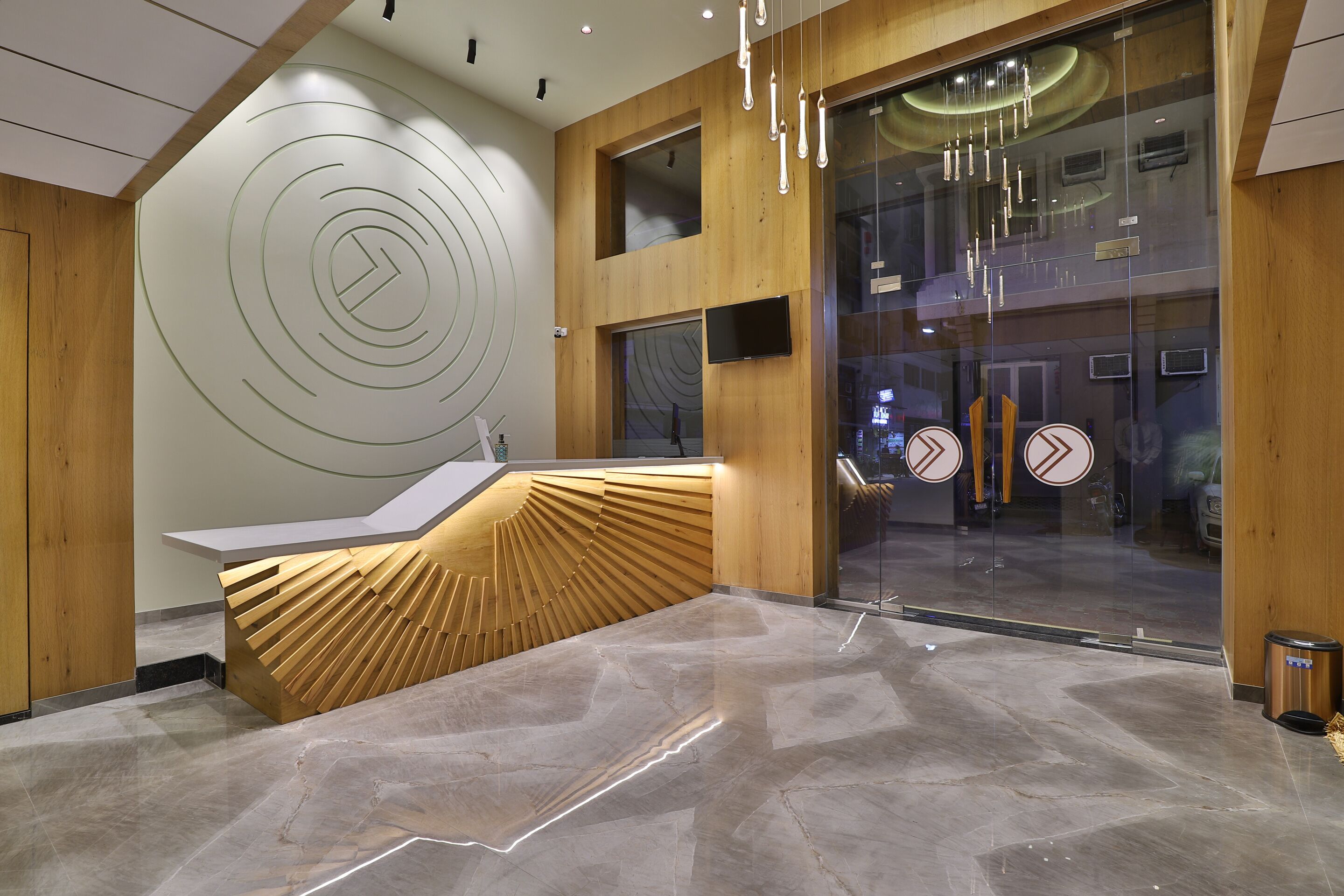 A modern reception area with a wooden reception desk, a glass wall with a view, and a circular design on the wall.