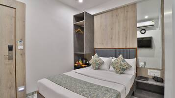 Une chambre d’hôtel moderne équipée d’un lit, d’une armoire, d’une table de chevet avec une lampe et d’un téléviseur fixé au mur.