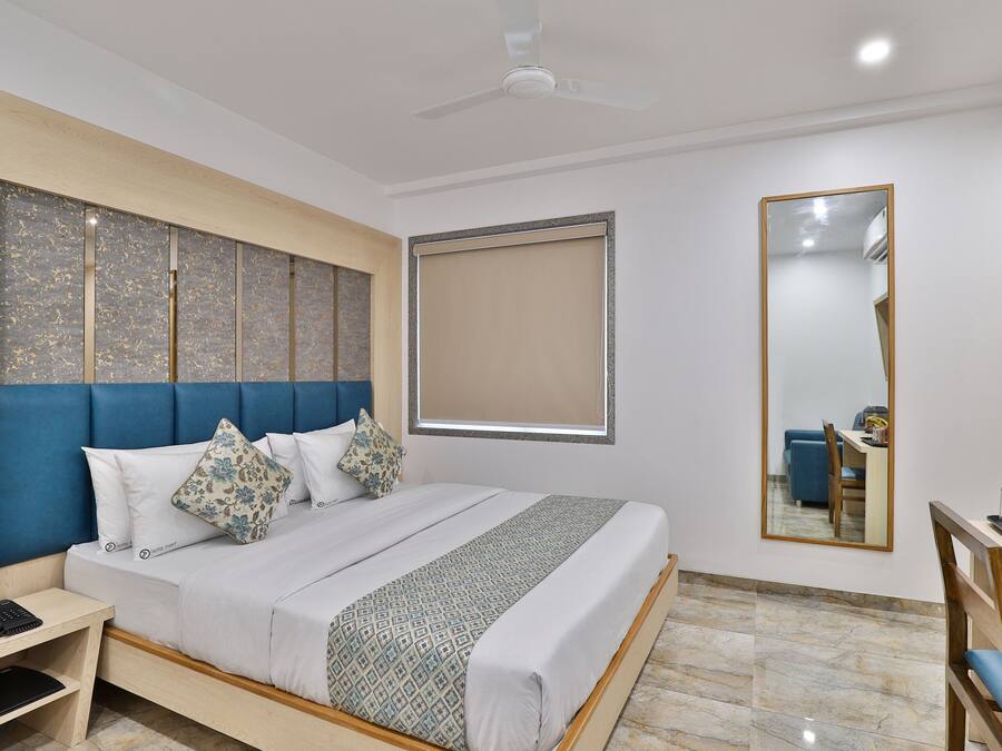 A modern hotel room with a large bed, a desk, and a chair.